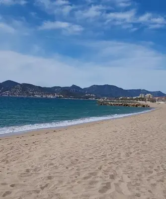 a sandy beach with the ocean and mountains in the background at Appartement proche de la plage in Cannes