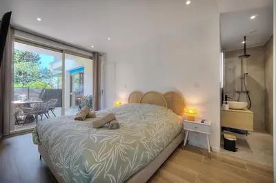 a bedroom with a large bed and a balcony at Le Greg - Terrasse - Parking - VCA in Cannes