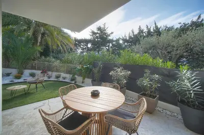 a wooden table and chairs on a patio with plants at Le Greg - Terrasse - Parking - VCA in Cannes