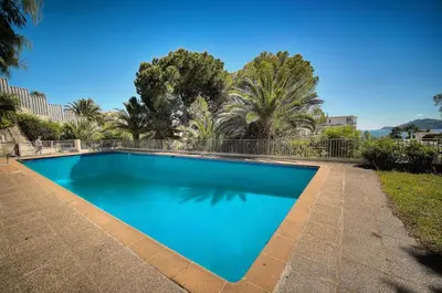 a blue swimming pool with trees in the background at Le Greg - Terrasse - Parking - VCA in Cannes