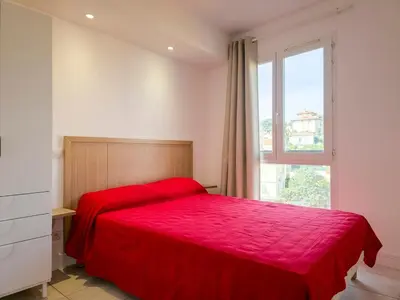 a bedroom with a red bed and a window at A022 Chic Cannes Flat Balcony Parking in Cannes