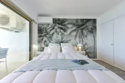 a bedroom with a large white bed with a palm mural at 2-Br sea view private parking walk to beaches in Cannes