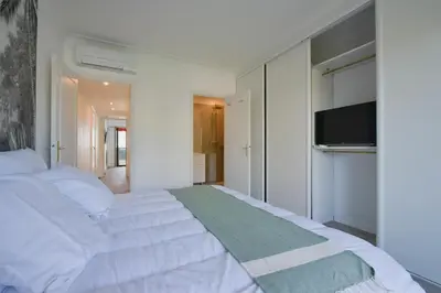 a bedroom with a white bed and a flat screen tv at 2-Br sea view private parking walk to beaches in Cannes