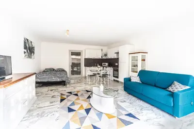 a living room with a blue couch and a kitchen at Grand studio centre-ville cannes aperçu mer in Cannes