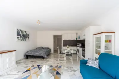 a living room with a blue couch and a kitchen at Grand studio centre-ville cannes aperçu mer in Cannes