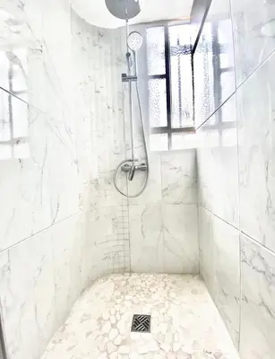 a white bathroom with a shower with a drain at Appartement Cosy in Le Cannet