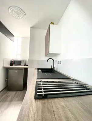 a kitchen with white walls and a sink and a counter at Appartement Cosy in Le Cannet