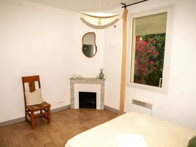 a bedroom with a fireplace and a chair and a mirror at La maison by Simone T3 in Cannes