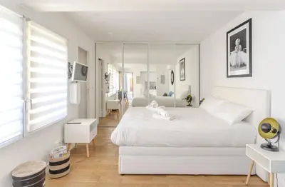 a white bedroom with a white bed and a mirror at Modern and renovated apartments next to the CROISETTE and PALAIS DES FESTIVALS in Cannes