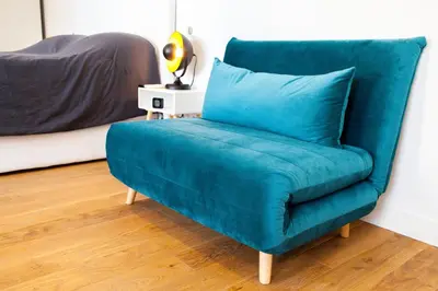 a blue chair in a room with a bed at Modern and renovated apartments next to the CROISETTE and PALAIS DES FESTIVALS in Cannes