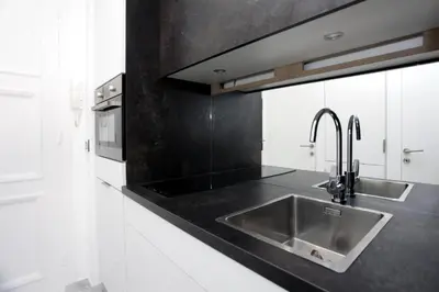a kitchen with a sink and a black counter top at LA CROISETTE élégant studio avec balcon et vue mer aperçu in Cannes