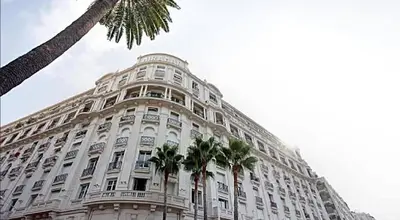 a large white building with palm trees in front of it at LA CROISETTE élégant studio avec balcon et vue mer aperçu in Cannes