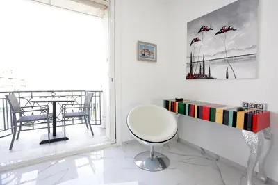 a white room with a book shelf and a chair at LA CROISETTE élégant studio avec balcon et vue mer aperçu in Cannes