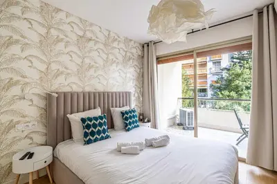 a bedroom with a large bed with blue and white pillows at LE FLEURI avec terrasse, à côté du Martinez, idéal pour un séjour plaisant in Cannes