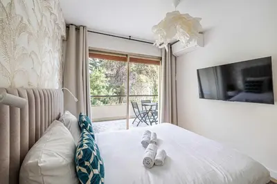 a bedroom with a bed with two rolled towels on it at LE FLEURI avec terrasse, à côté du Martinez, idéal pour un séjour plaisant in Cannes