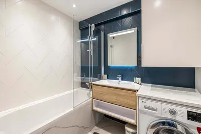 a bathroom with a sink and a washing machine at LE FLEURI avec terrasse, à côté du Martinez, idéal pour un séjour plaisant in Cannes