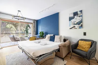 a bedroom with a large bed and a couch at LE FLEURI avec terrasse, à côté du Martinez, idéal pour un séjour plaisant in Cannes