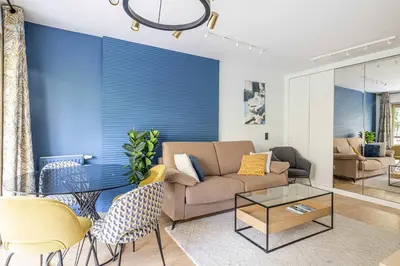 a living room with a couch and a blue wall at LE FLEURI avec terrasse, à côté du Martinez, idéal pour un séjour plaisant in Cannes