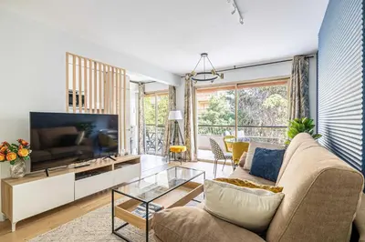 a living room with a couch and a tv at LE FLEURI avec terrasse, à côté du Martinez, idéal pour un séjour plaisant in Cannes