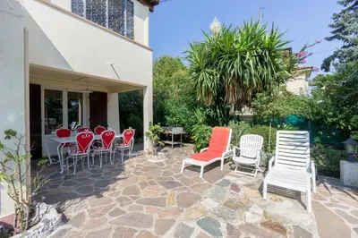 a patio with white chairs and tables and red chairs at La fourmi in Cannes