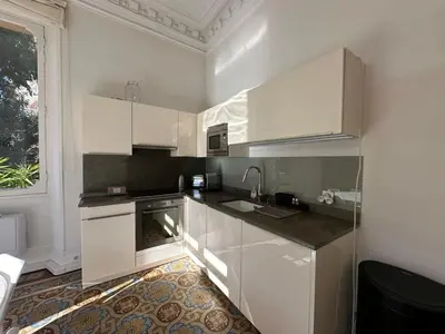 a kitchen with white cabinets and a sink and a window at C025 Villa Toscane Bel Appartement Bourgeois in Cannes