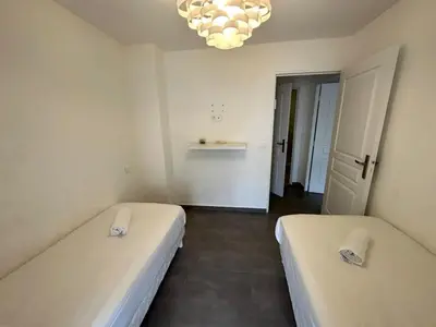 two beds in a small room with a chandelier at C058 Bel appartement spacieux terrasse Centre in Cannes