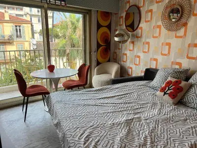 a bedroom with a bed and a table and a window at Studio next to the beach in Cannes