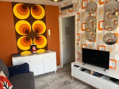 a living room with a television and a wall with orange at Studio next to the beach in Cannes