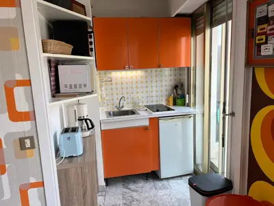 a small kitchen with orange cabinets and a sink at Studio next to the beach in Cannes