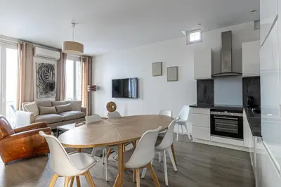 a kitchen and living room with a wooden table and chairs at 64m2 face Majestic - 50m palais & plages in Cannes