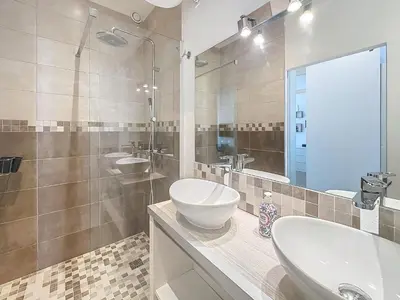a bathroom with two sinks and a glass shower at 64m2 face Majestic - 50m palais & plages in Cannes