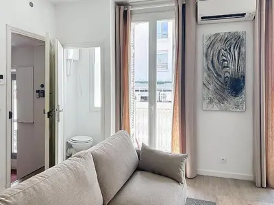 a living room with a couch in front of a window at 64m2 face Majestic - 50m palais & plages in Cannes
