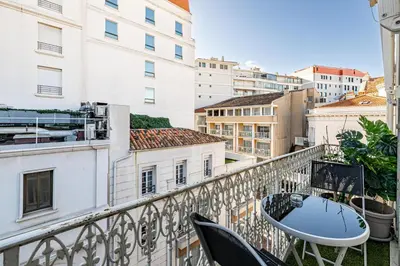 a balcony with a table and chairs and buildings at 64m2 face Majestic - 50m palais & plages in Cannes