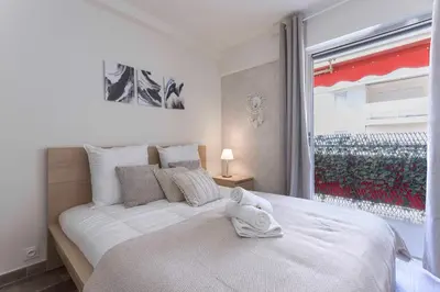 a bedroom with a large white bed with a window at Amandier du Moure Rouge in Cannes