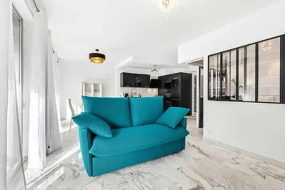 a blue couch in a living room with white walls at SUNBLUE - Accommodation Center Cannes & port in Cannes