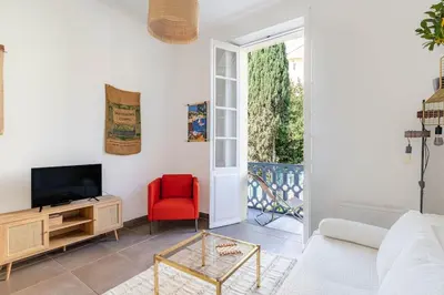 a living room with a tv and a red chair at Le Louis- Superbe logement à 5mins des plages, proche Palais in Cannes