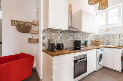 a kitchen with white cabinets and a red chair at Le Louis- Superbe logement à 5mins des plages, proche Palais in Cannes