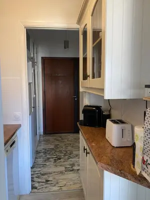 a kitchen with white cabinets and a hallway leading to a door at Cannes centre Lou Souquetan in Cannes