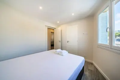 a white bed in a room with a window at Centre ville Croisette in Cannes