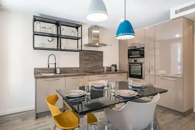 a kitchen with a glass table and yellow chairs at Centre ville Croisette in Cannes