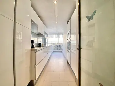 a kitchen with white cabinets and a long hallway at Grand Hotel 2 chambres 2 sdb - GH in Cannes
