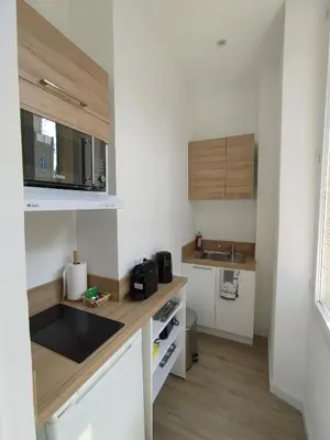 a small kitchen with white cabinets and a sink at Studio mezzanine in Cannes