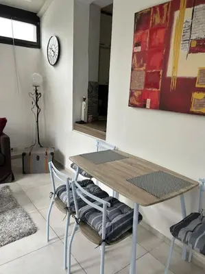a table and chairs in a room with a clock on the wall at Résidence Cannes Plage Business Saisonnier in Cannes