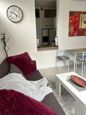 a living room with a couch and a clock on the wall at Résidence Cannes Plage Business Saisonnier in Cannes