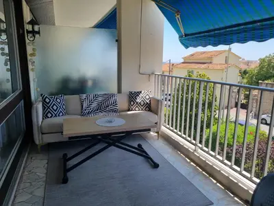 a porch with a couch and a table on a balcony at Spacieux 2 pièces terrasse et piscine in Cannes