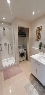 a bathroom with a shower and a washing machine at Spacieux 2 pièces terrasse et piscine in Cannes