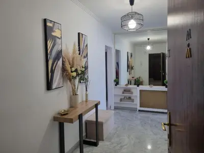 a hallway with a table with flowers on a wall at Spacieux 2 pièces terrasse et piscine in Cannes