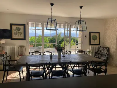 a dining room with a large wooden table and chairs at La Pastourelle in Le Cannet