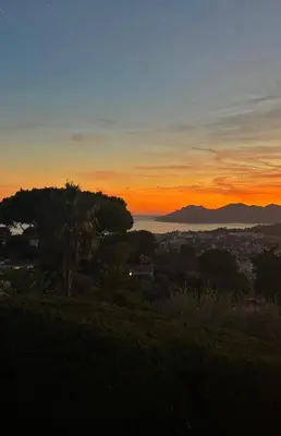a sunset view of the ocean and a city at La Pastourelle in Le Cannet