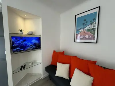 a living room with a red couch and a fish tank at Studio confortable proche mer deb1890 in Cannes
